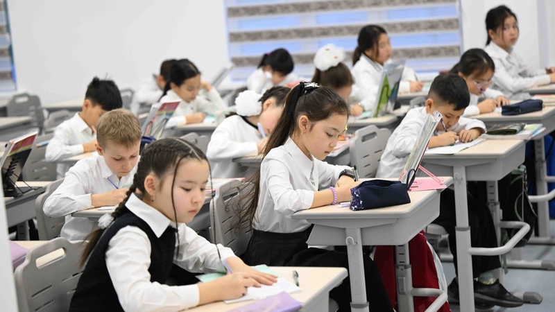 Students in white uniforms focused on their studies in a modern classroom setting
